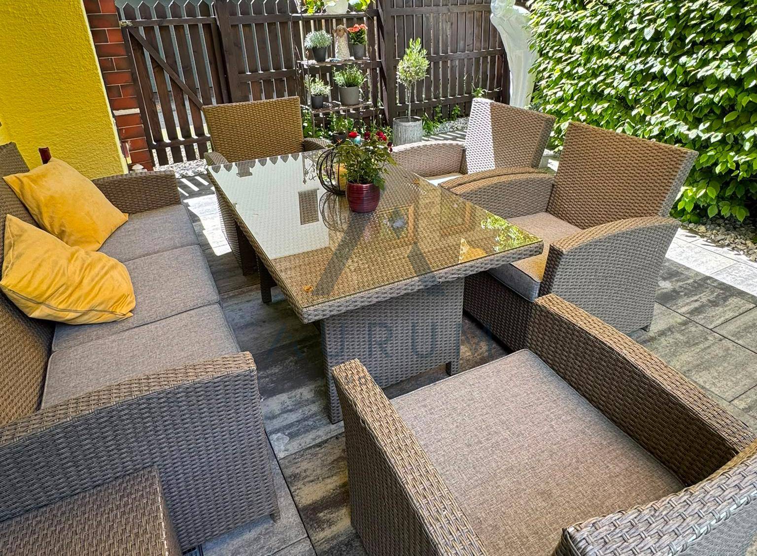 Gemütliche Terrasse mit Rattanmöbeln und Esstisch im Freien.