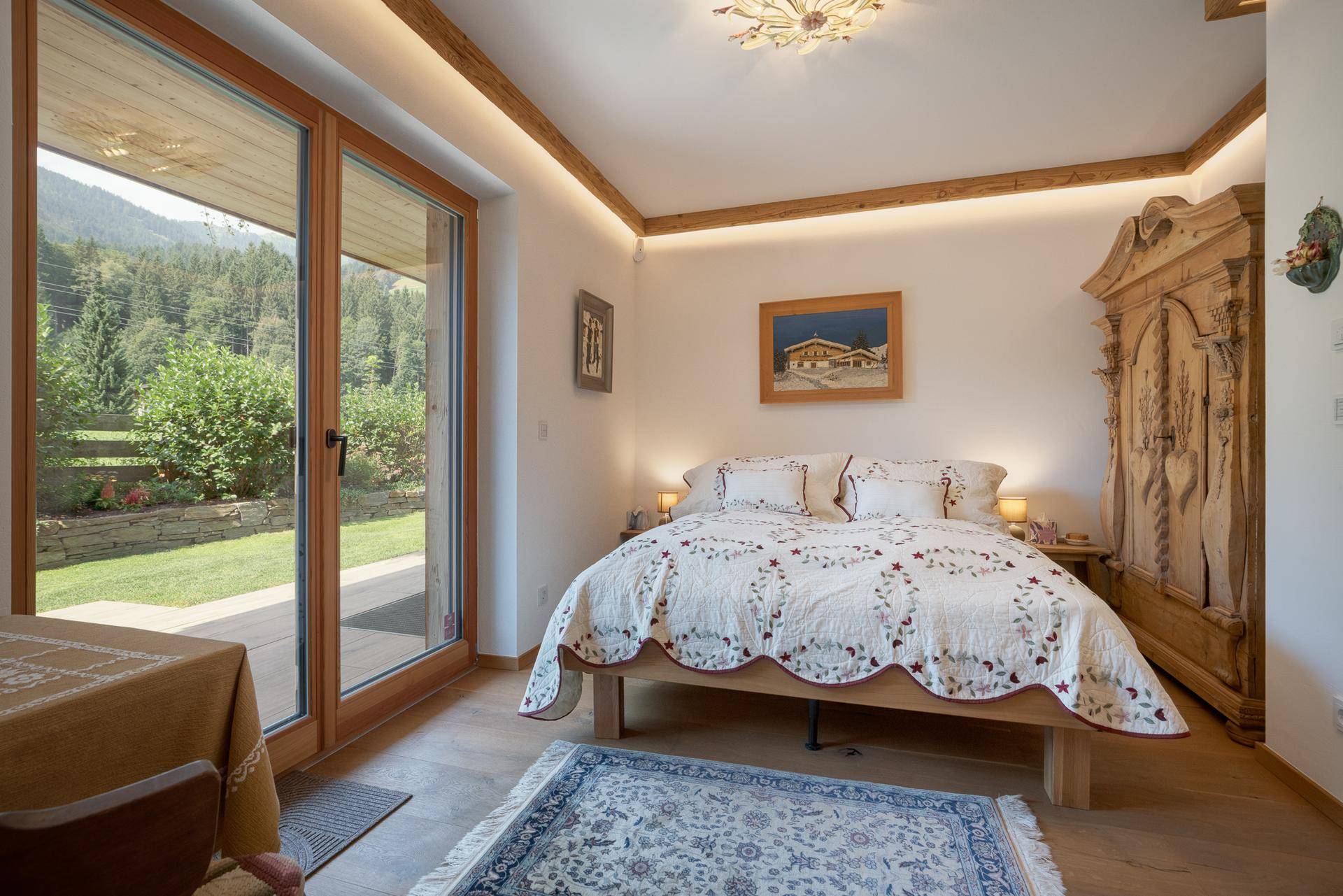 Helles Schlafzimmer mit Zugang zum Garten, Holzboden und traditionellen Möbeln.