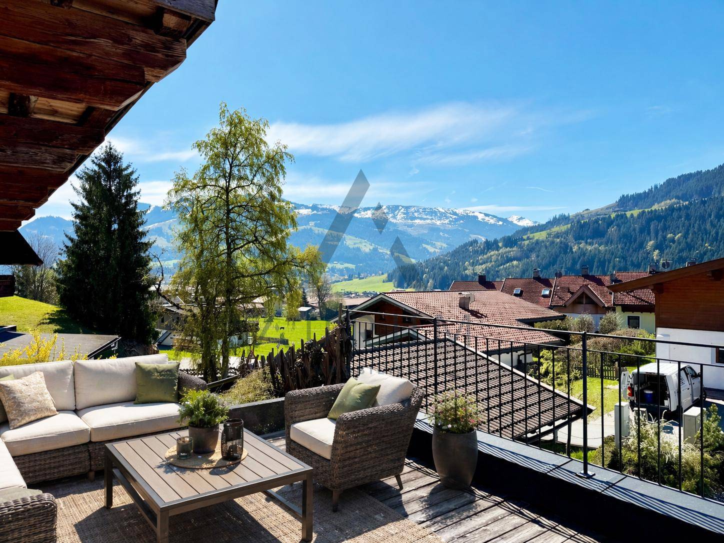 Sonnige Terrasse mit bequemen Gartenmöbeln und Panoramablick auf die umliegende Bergwelt.