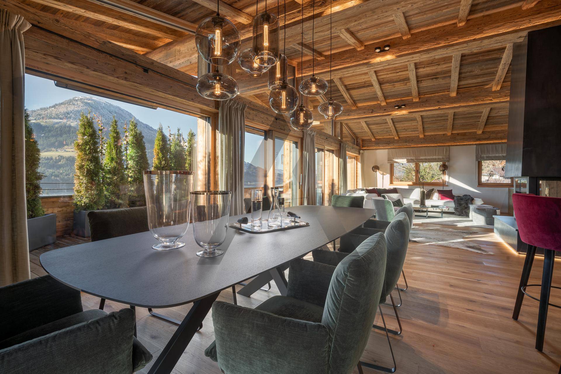 Moderner Essbereich mit großem Tisch und Blick auf die umliegende Berglandschaft durch bodentiefe Fenster.