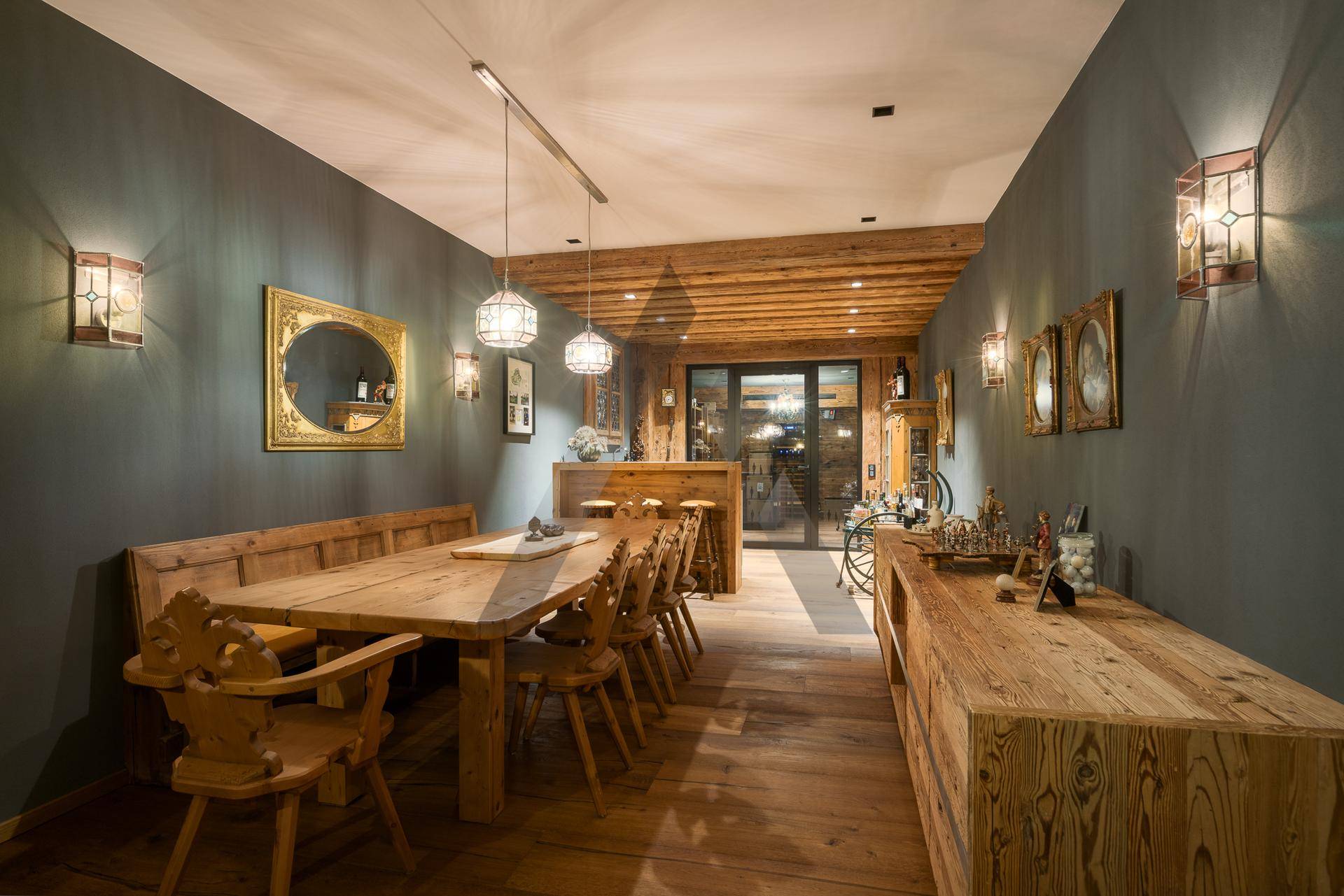 Rustikaler Essbereich mit Holztisch, Bänken und traditioneller Wanddekoration.