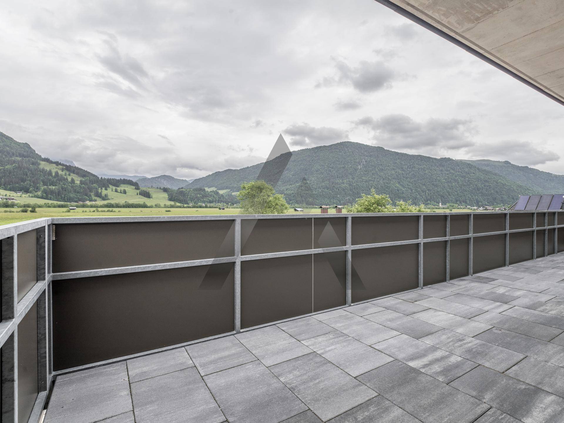 Breiter Balkon mit Fliesenboden und robustem Geländer, ideal für Entspannung mit Bergblick.