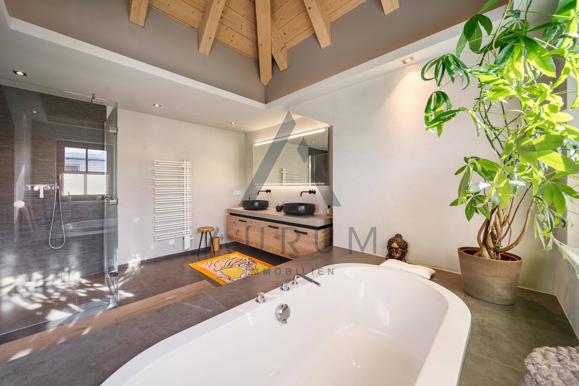 Geräumiges Badezimmer mit freistehender Badewanne, Doppelwaschbecken und Holzbalkendecke.
