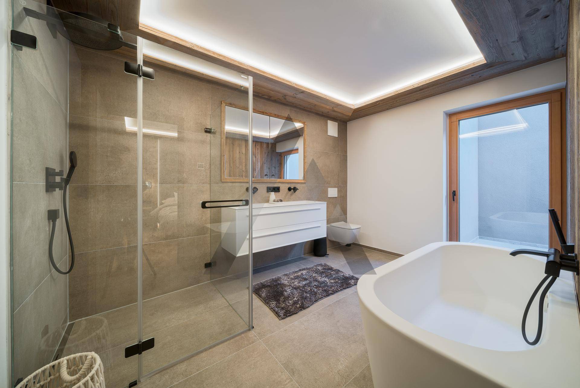 Geräumiges Badezimmer mit freistehender Badewanne, begehbarer Dusche und Holzdecke.