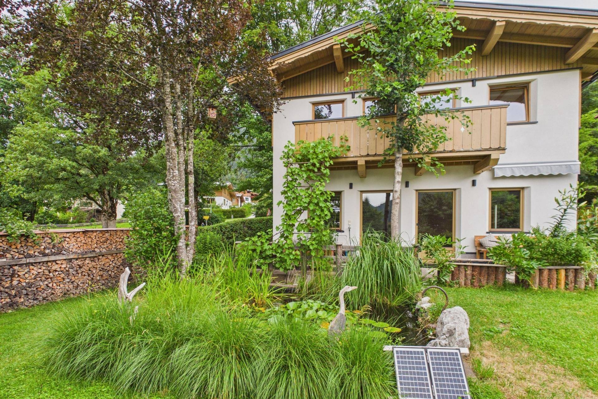 Garten mit Teich, üppiger Bepflanzung und Solarpaneelen zur Energiegewinnung.