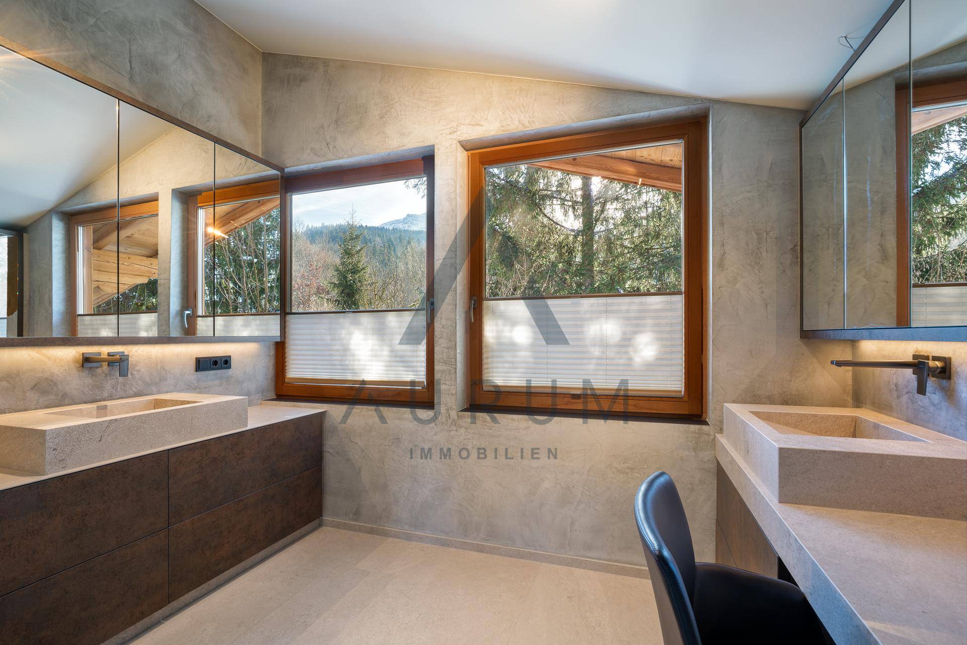 Geräumiges Badezimmer mit Doppelwaschbecken, Spiegelschränken und Fenstern mit Waldblick.