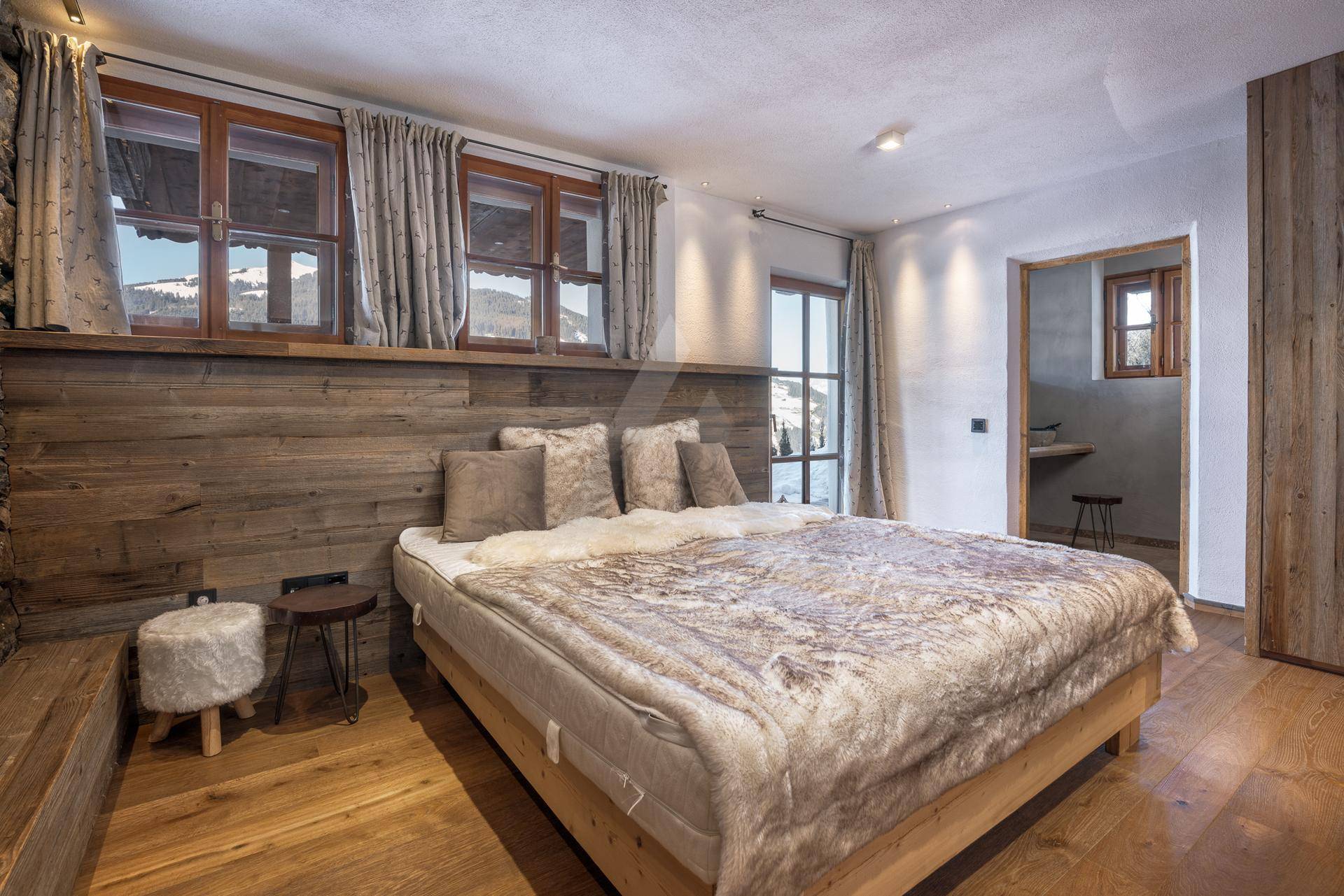 Schlafzimmer mit Holzwand, Holzboden und Zugang zu einem Balkon mit Bergblick.