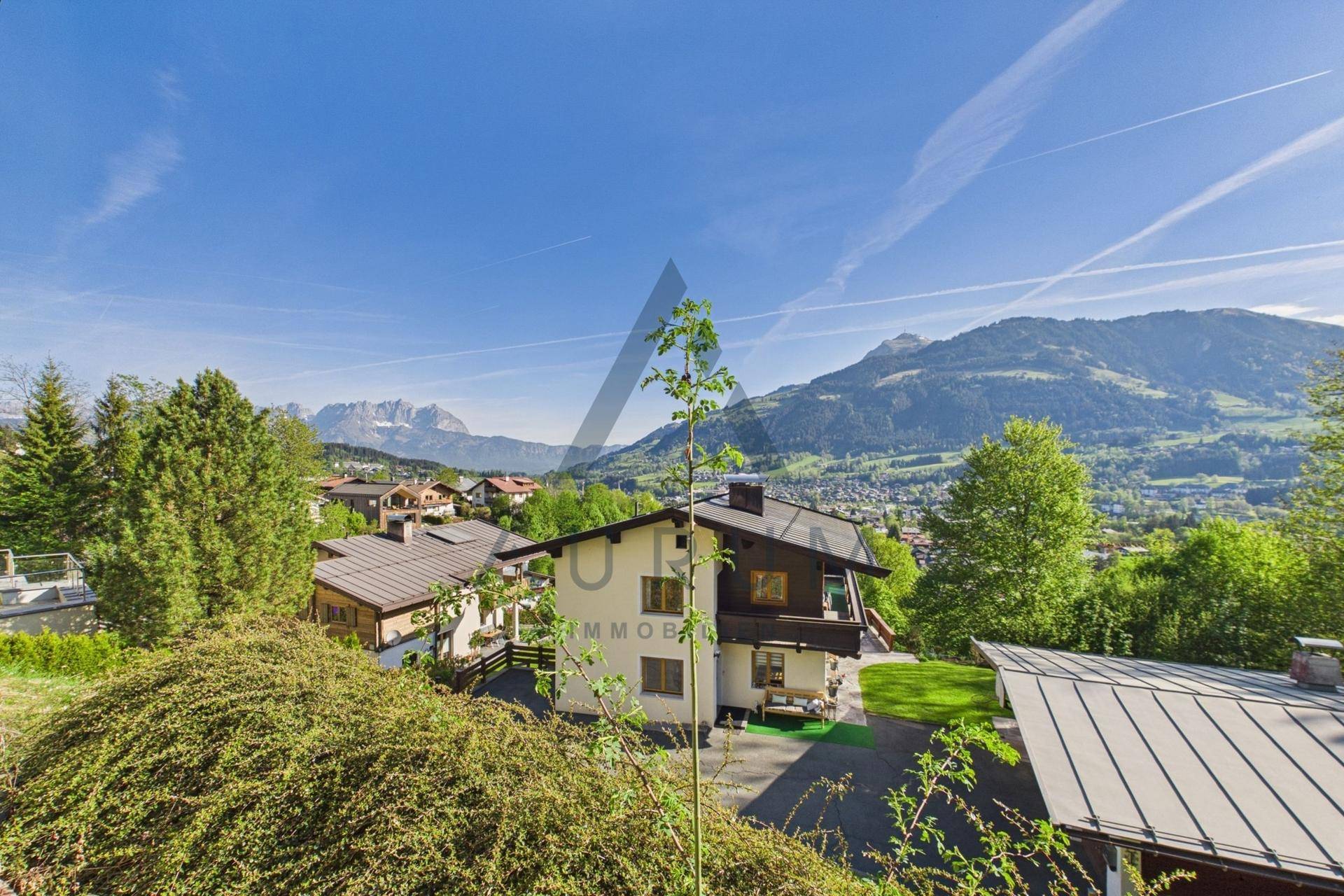Panoramablick auf ein charmantes Haus mit umliegenden Gebäuden und einer weiten Berglandschaft.