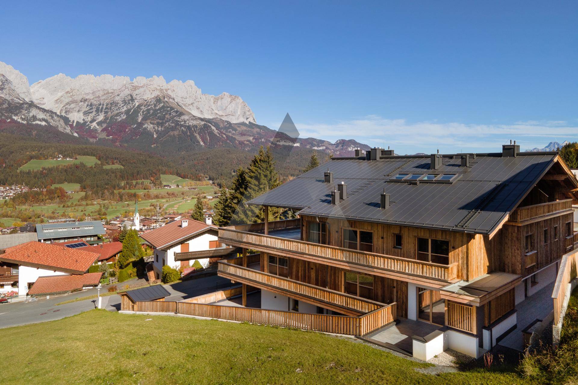 Großzügiges Holzhaus in alpiner Umgebung mit mehreren Balkonen und Bergblick.