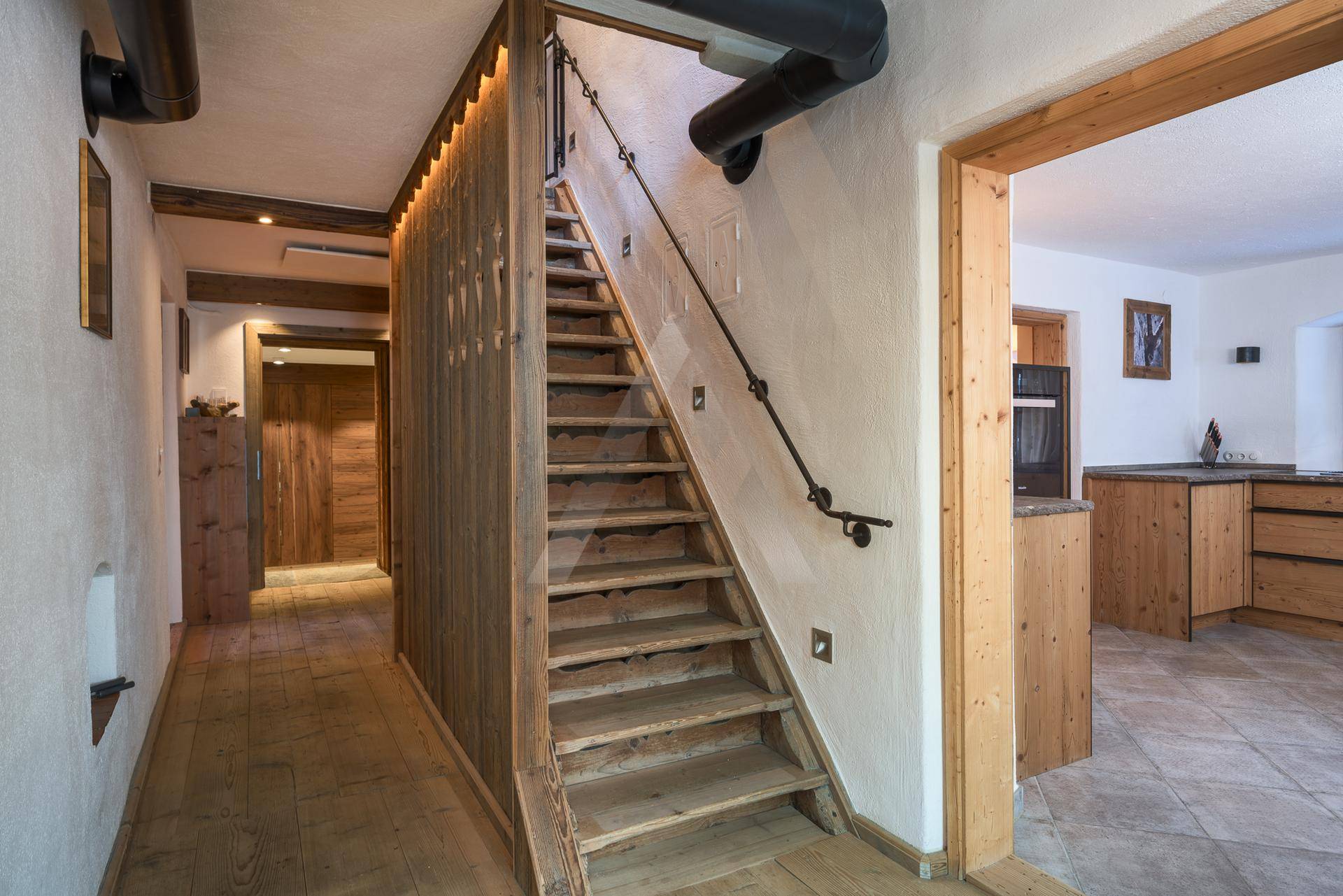 Rustikaler Flur mit Holztreppe, Holzboden und Zugang zu weiteren Räumen.
