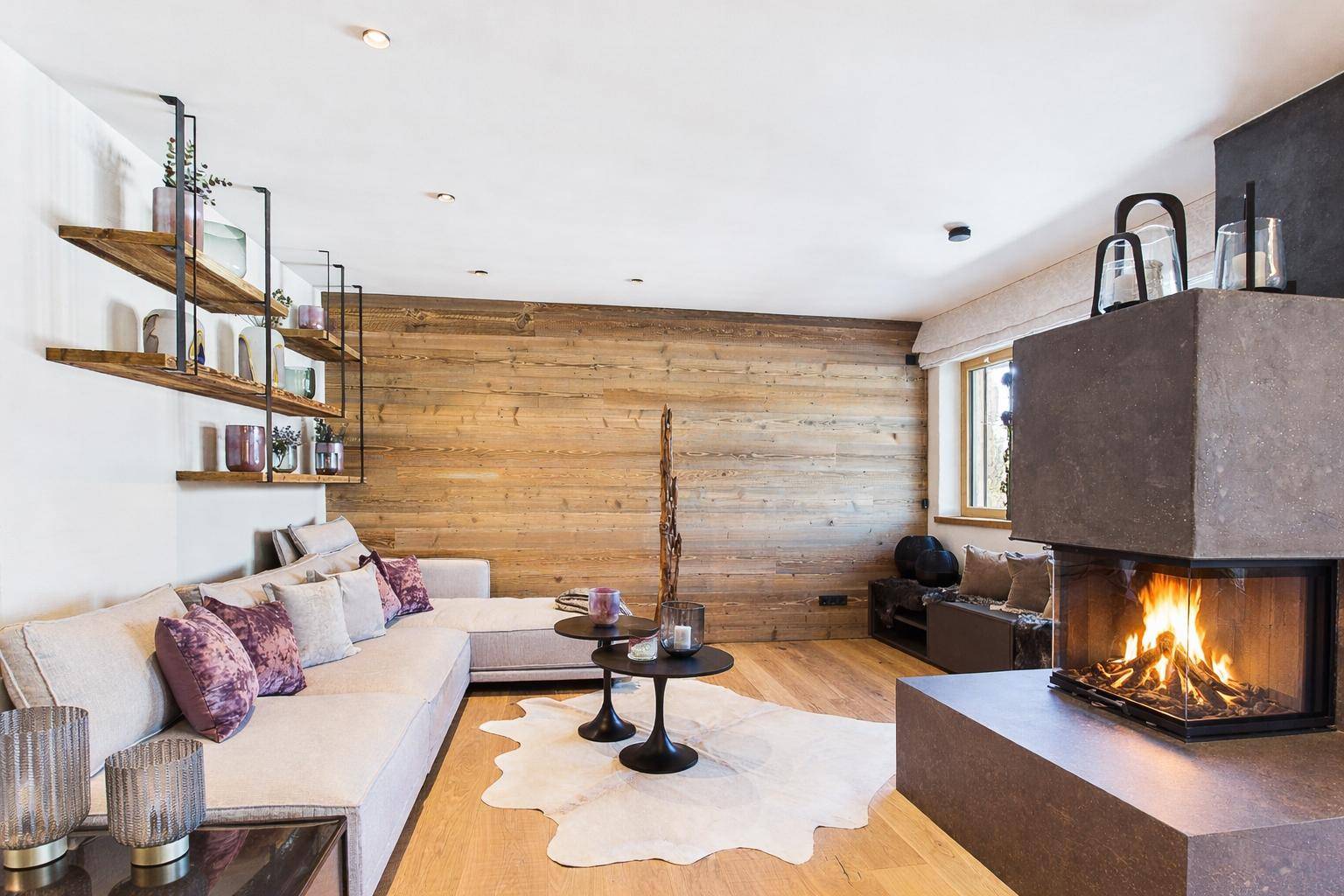 Helles Wohnzimmer mit Kamin, Holzwand und bequemer Sitzecke.