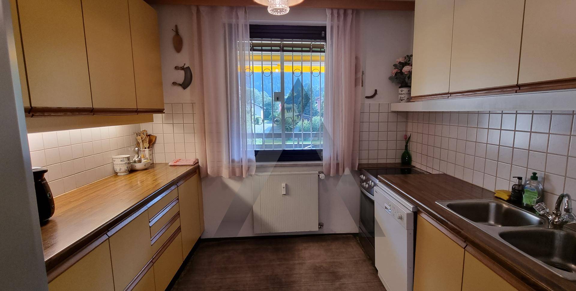 Küche mit Holz-Arbeitsplatten, hellen Schränken und einem Fenster mit Blick ins Grüne