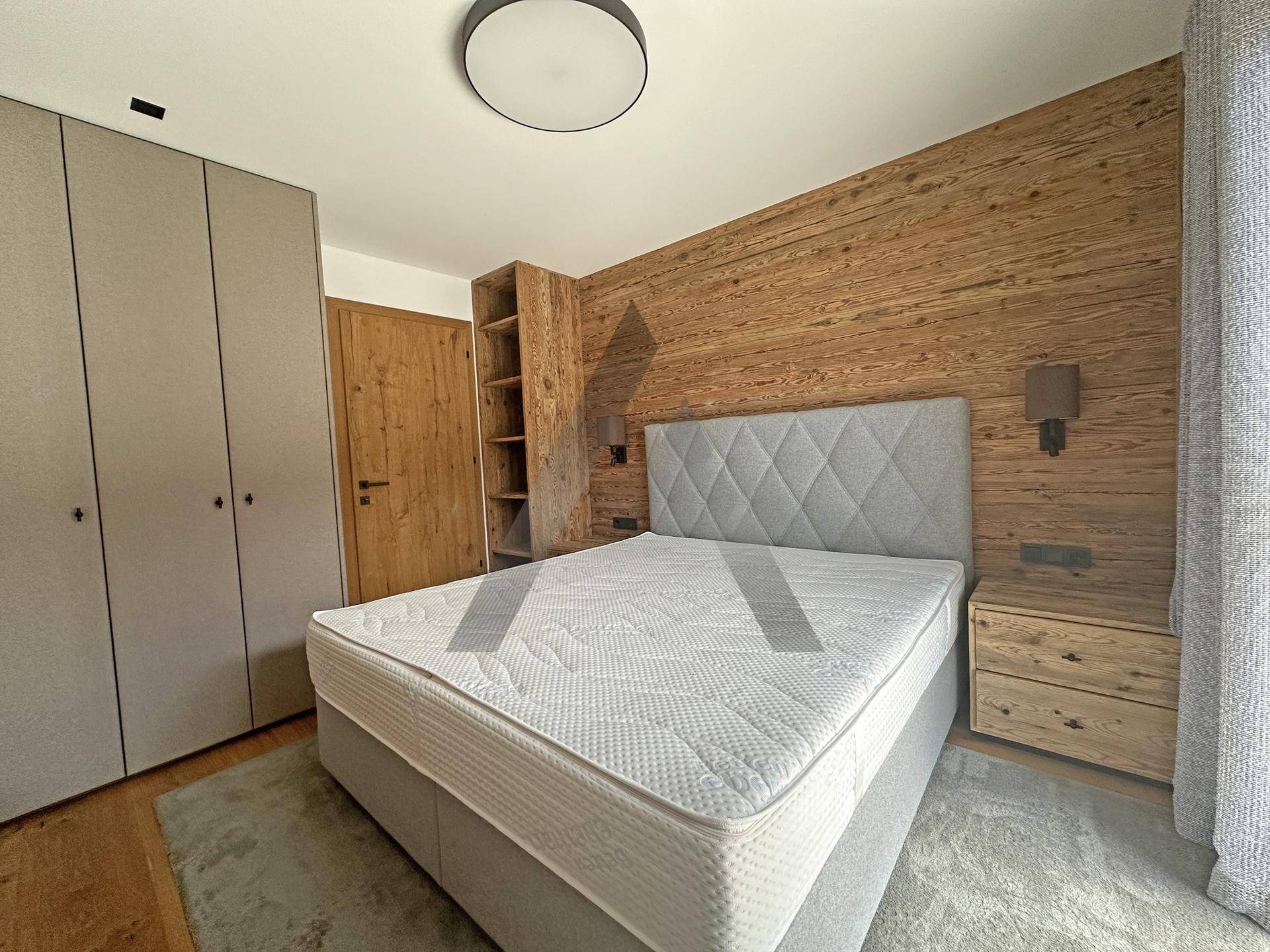 Modernes Schlafzimmer mit Holzwänden, bequemen Bett und integrierten Schränken.