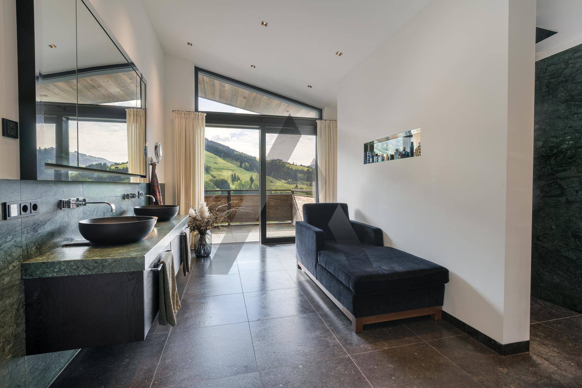 Modernes Badezimmer mit Doppelwaschbecken, dunklen Fliesen und Bergblick vom Balkon.