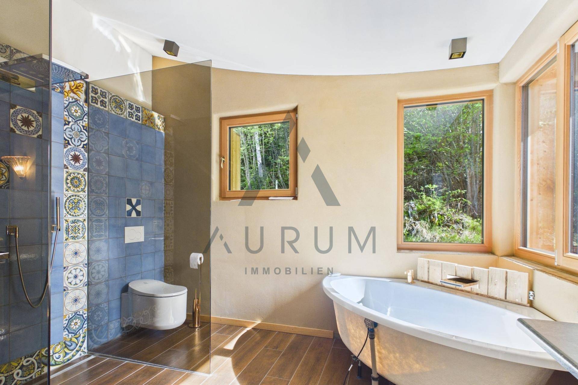 Modernes Badezimmer mit freistehender Badewanne, begehbarer Dusche und Blick ins Grüne.