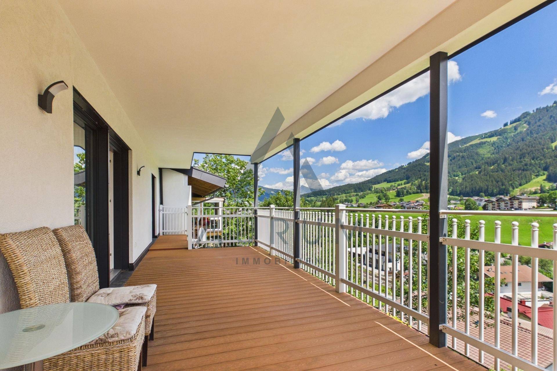 Geräumiger Balkon mit Holzboden und Sitzgelegenheiten, bietet einen weiten Bergblick.