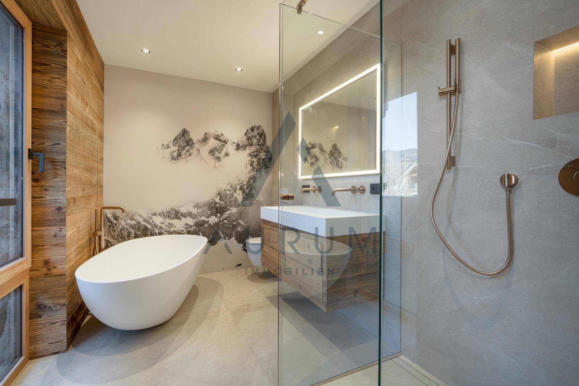 Luxuriöses Badezimmer mit freistehender Badewanne, begehbarer Dusche und Bergmotiv-Tapete.
