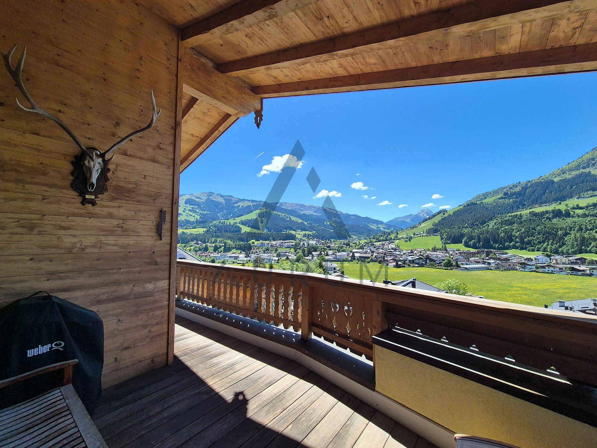 Geräumiger Holzbalkon mit Grillbereich und atemberaubendem Blick auf die umliegende Bergwelt und das Tal.