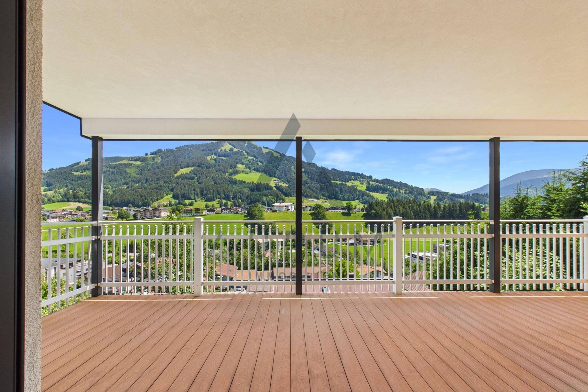 Geräumiger Balkon mit Holzboden und weitem Blick auf die umliegende Berglandschaft.