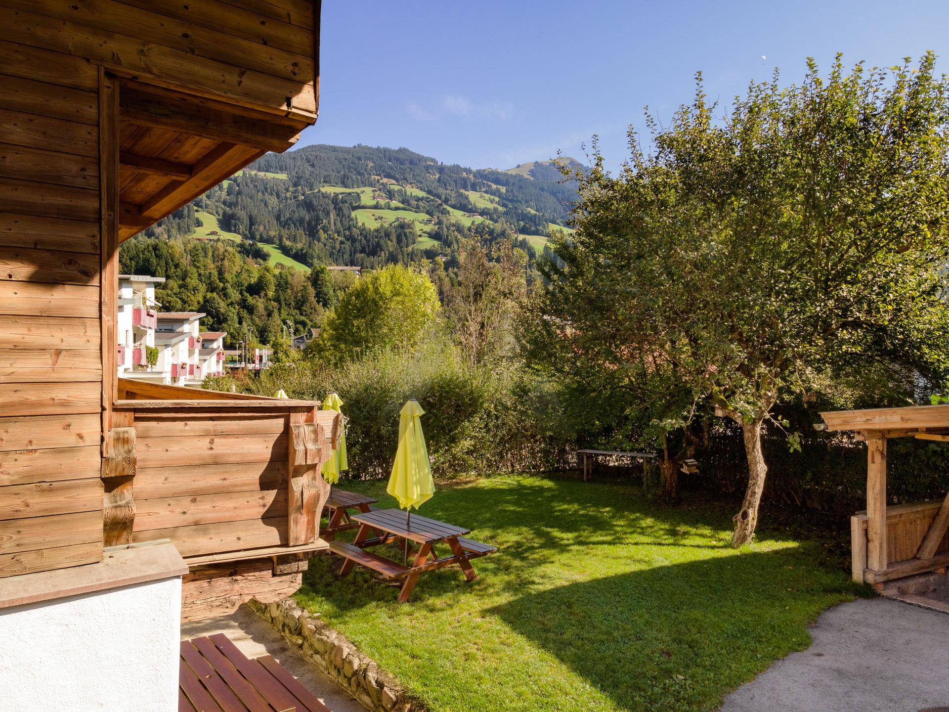 Sonniger Gartenbereich mit Picknicktischen und weitem Blick auf die umliegende Berglandschaft.
