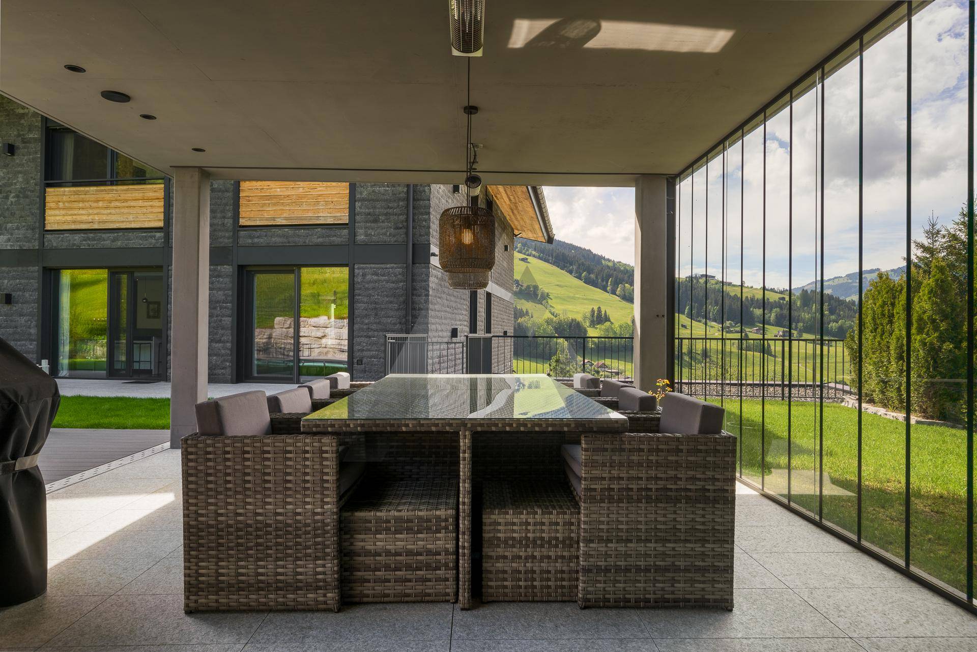 Überdachte Terrasse mit großem Esstisch und Panoramablick auf die umliegende Berglandschaft.
