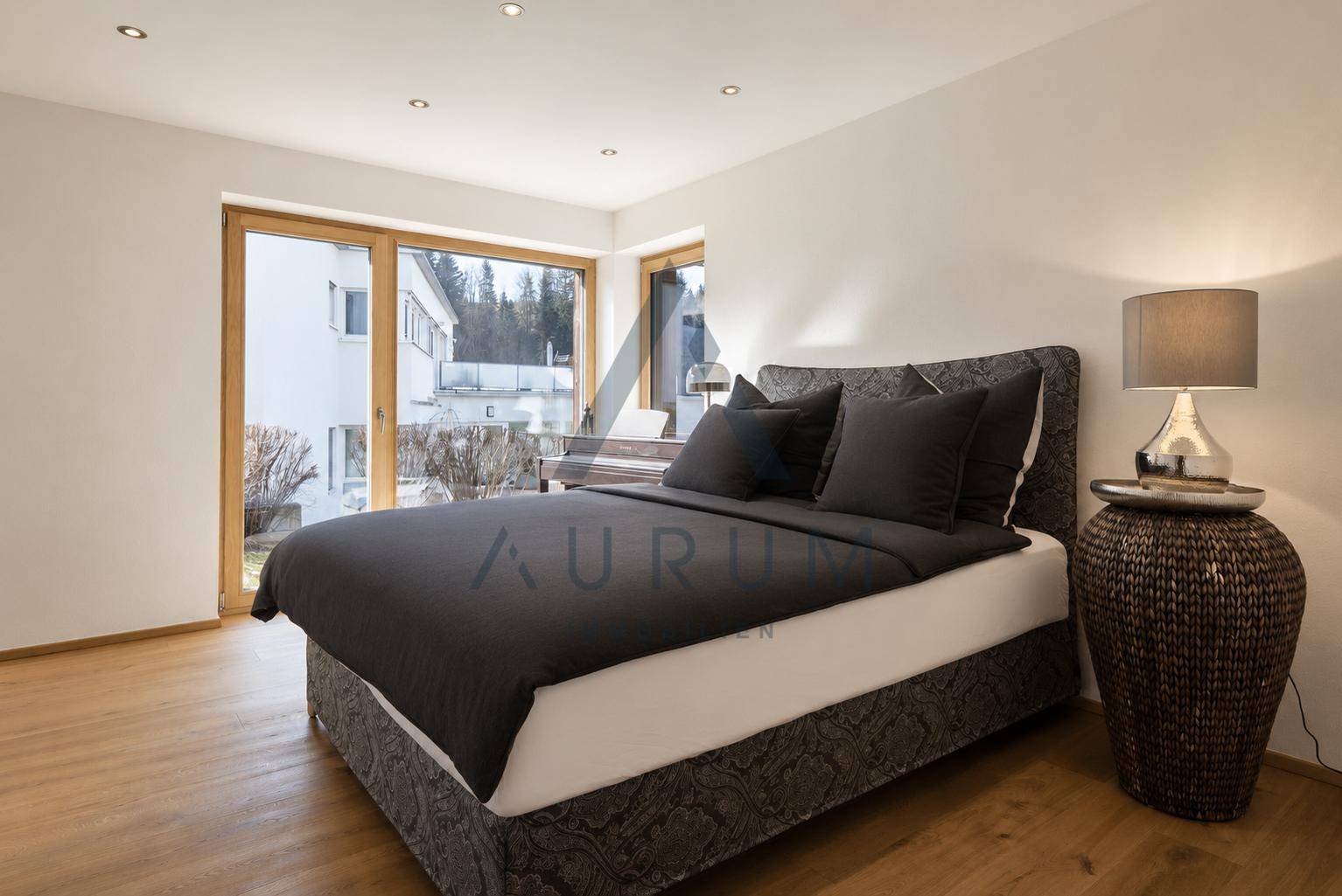 Helles Schlafzimmer mit Holzboden, großem Bett und Blick ins Grüne.