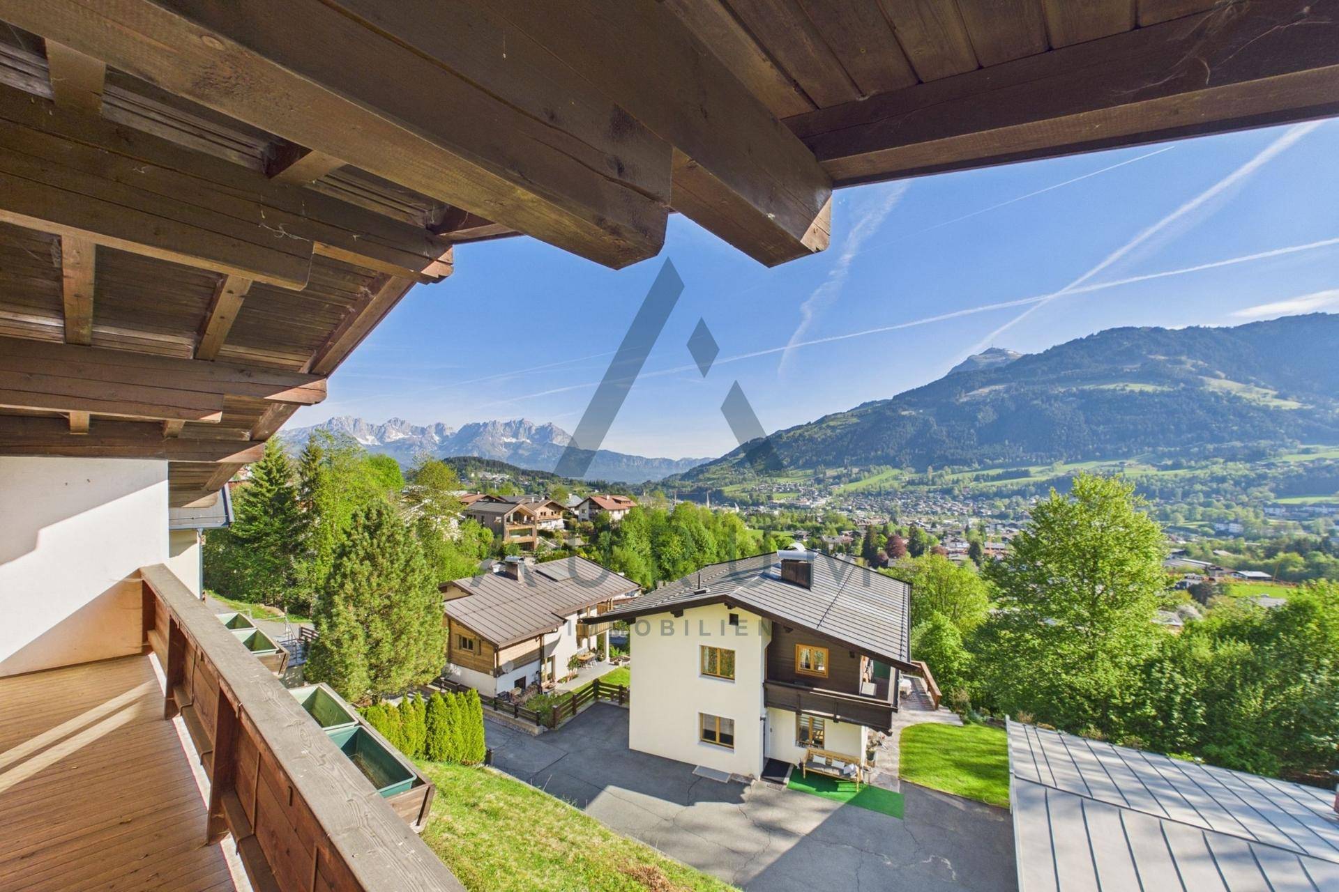 Balkon mit weitem Blick über die Berglandschaft und umliegende Häuser.
