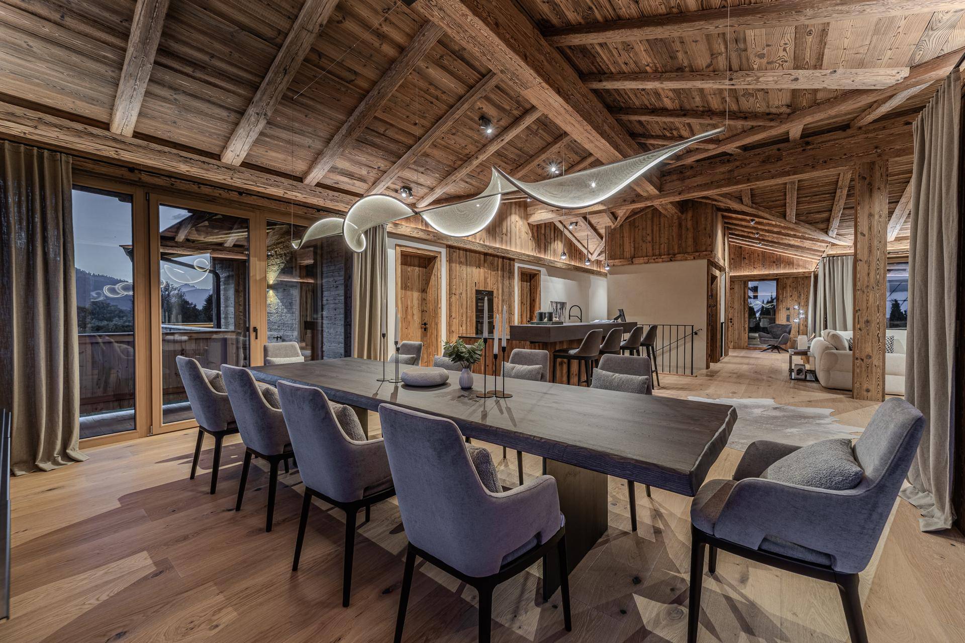 Eleganter Essbereich mit Holzbalkendecke, großem Holztisch und Panoramablick auf die Berge.