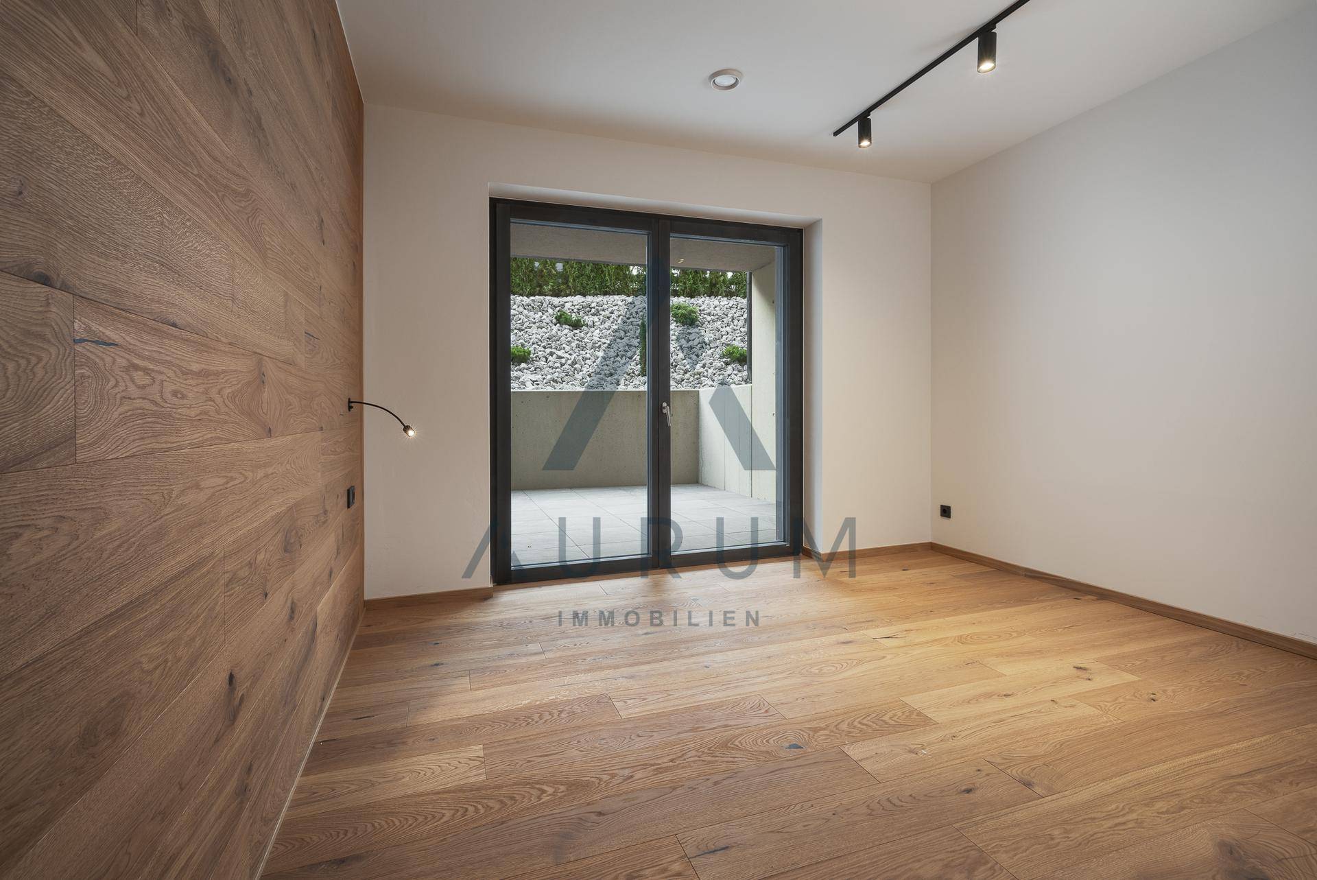 Helles Zimmer mit Holzboden und Zugang zu einem kleinen Außenbereich.