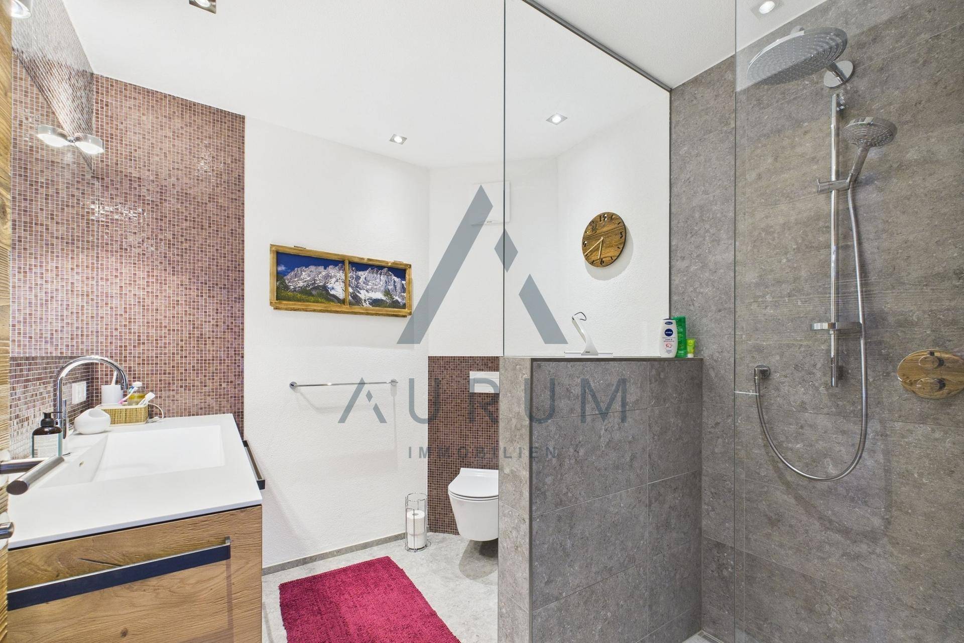 Modernes Duschbad mit begehbarer Dusche, Wand-WC und Mosaikfliesen.