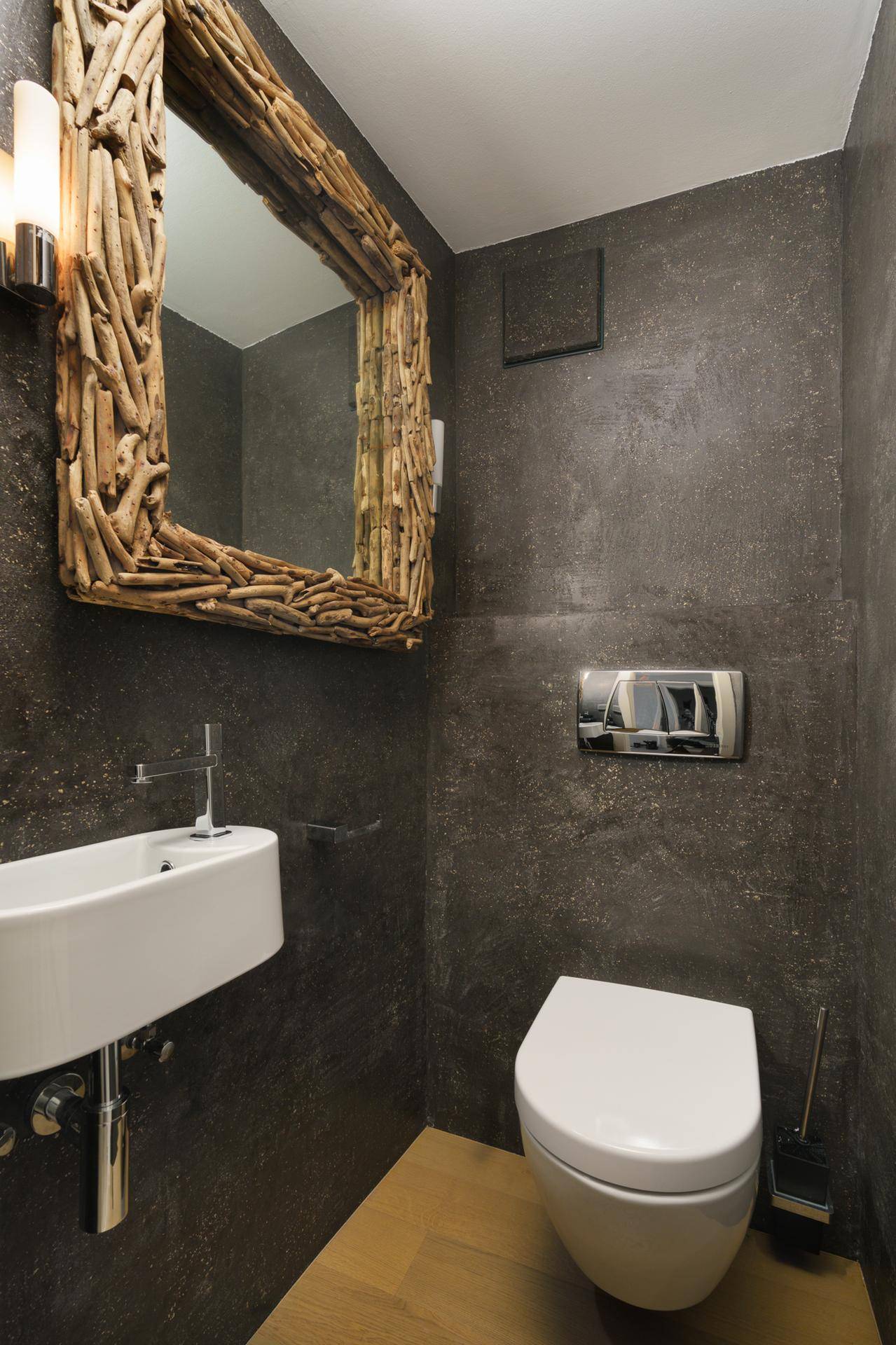 Stilvolles Gäste-WC mit dunklen Wänden, wandhängendem WC und einzigartigem Spiegel.