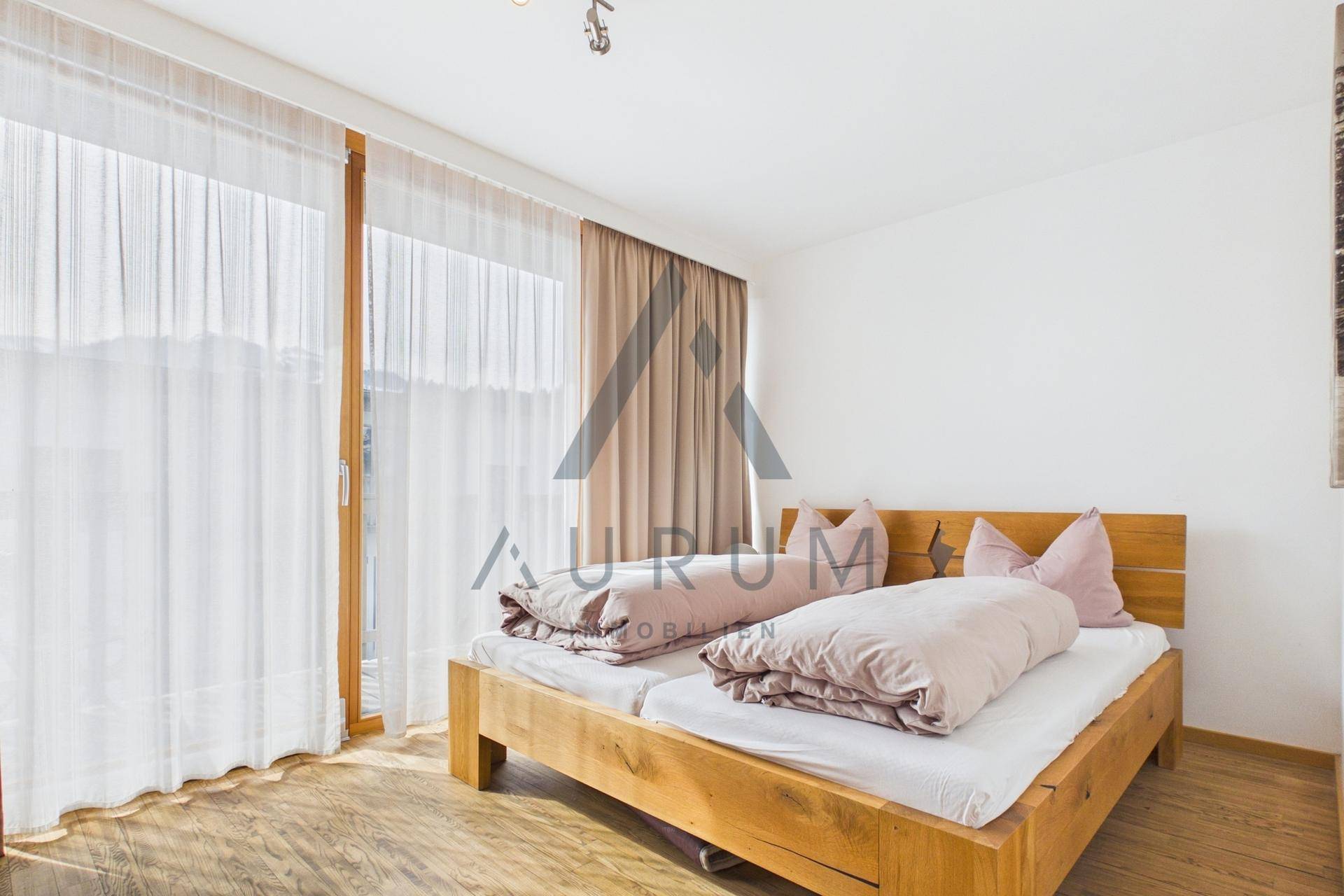 Schlafzimmer mit Holzbett, Holzboden und Zugang zu einem Balkon oder einer Terrasse.