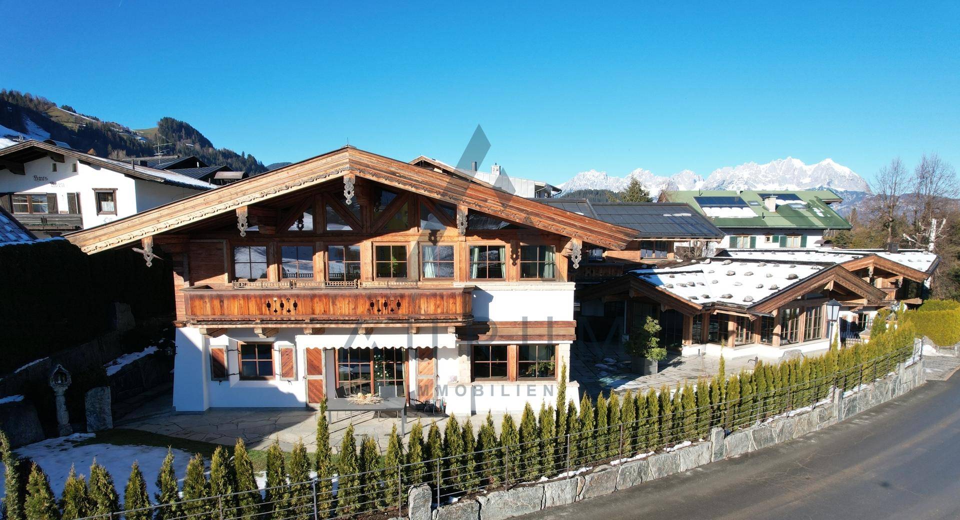 Charmantes Chalet mit traditioneller Holzfassade und Bergblick unter blauem Himmel.