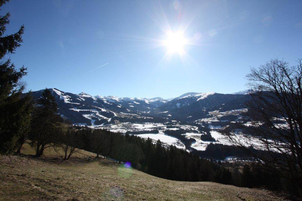 Weitläufiger Panoramablick über schneebedeckte Täler und majestätische Berge unter strahlend blauem Himmel.