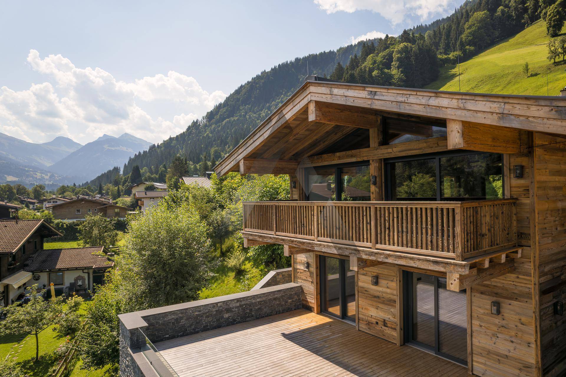 Luxuriöses Holzchalet mit Balkon und Terrasse, eingebettet in eine malerische Berglandschaft.