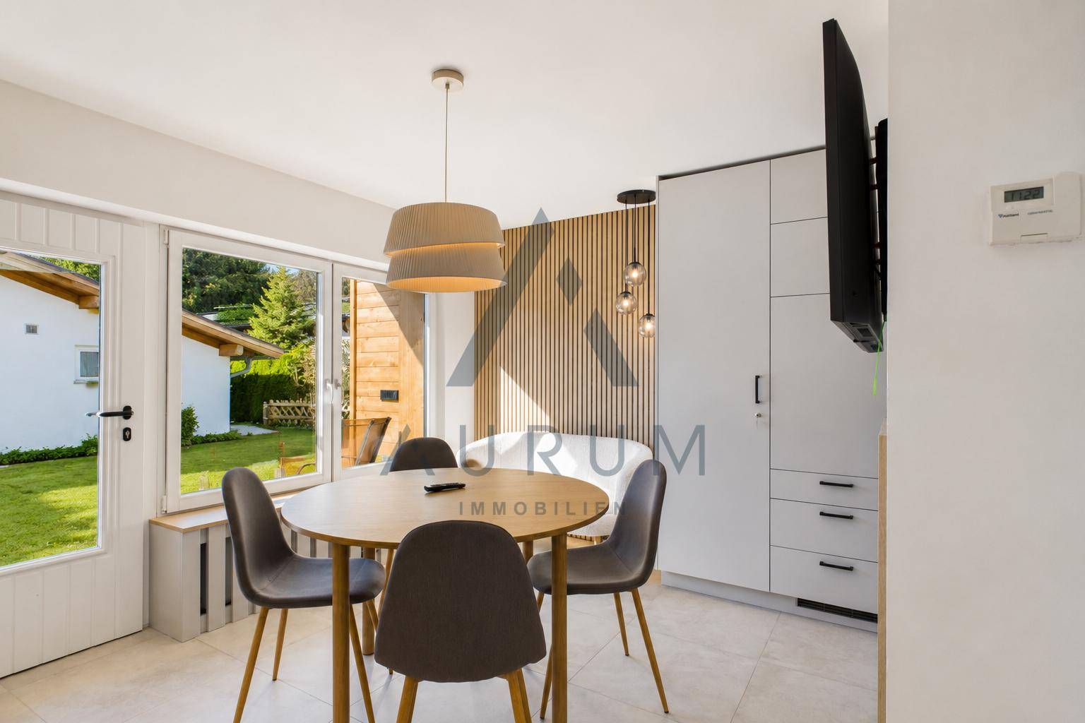 Heller Essbereich mit modernem Holztisch, Fliesenboden und Zugang zur Terrasse.