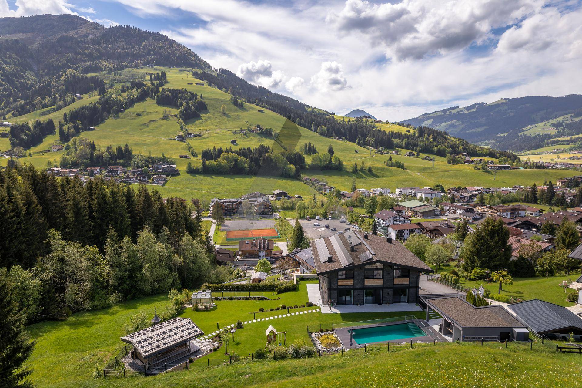 Weitläufiges Anwesen mit Pool und Tennisplatz, eingebettet in eine malerische Berglandschaft.