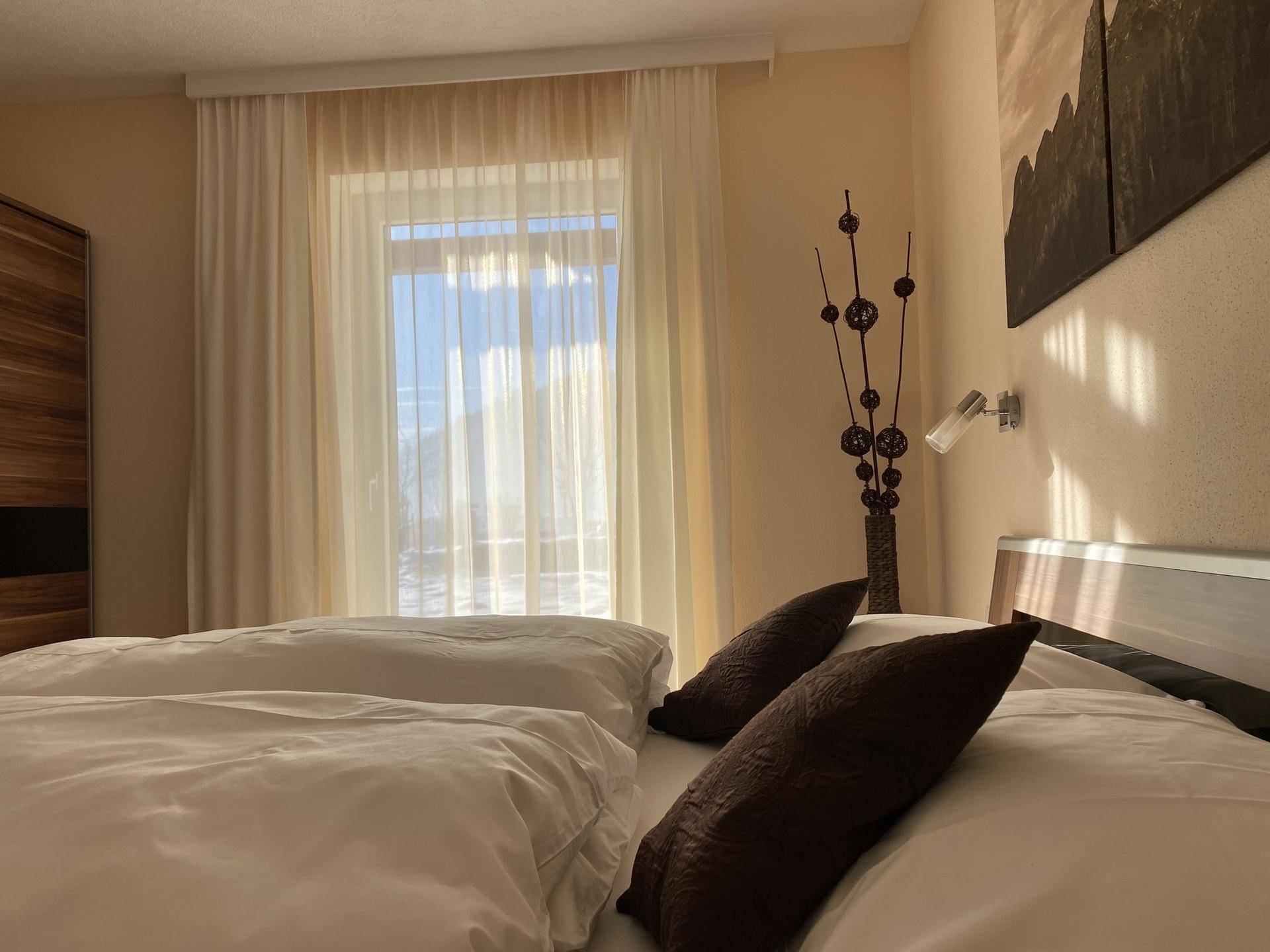 Gemütliches Schlafzimmer mit Doppelbett und großem Fenster, das viel Licht hereinlässt.