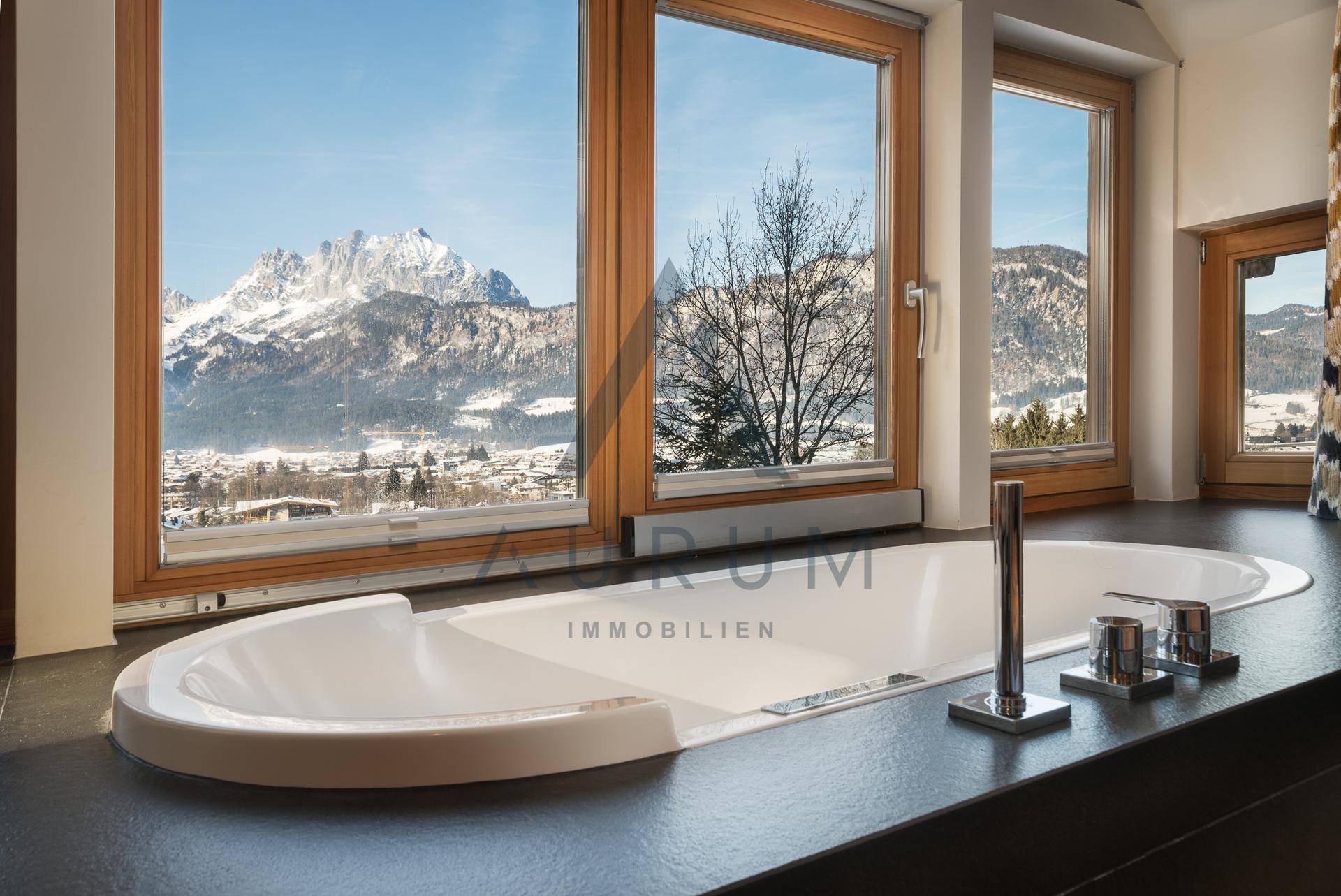 Modernes Badezimmer mit Badewanne und Panoramafenstern, die einen weiten Bergblick bieten.