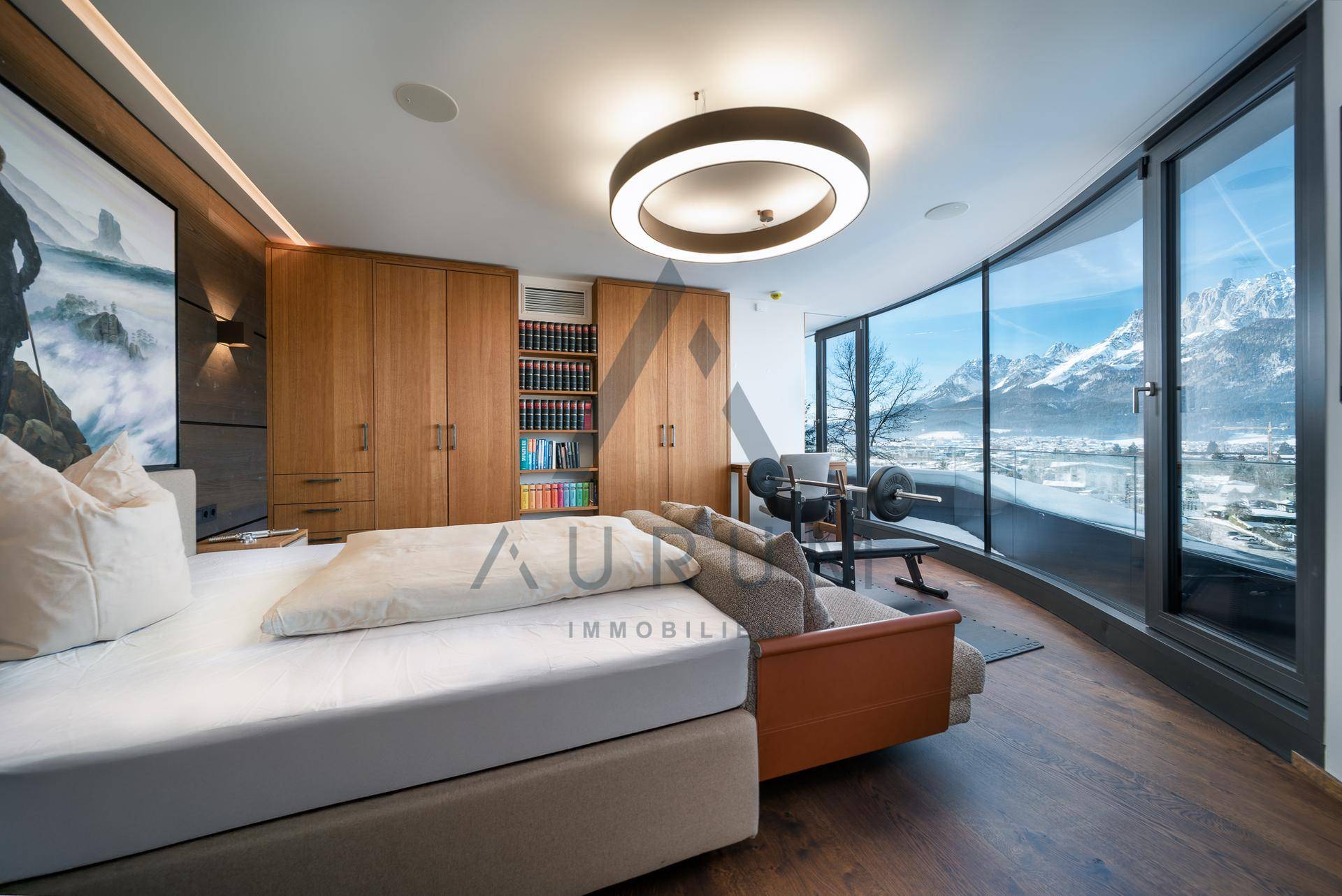 Geräumiges Schlafzimmer mit integriertem Fitnessbereich und beeindruckendem Bergblick durch große Fenster.