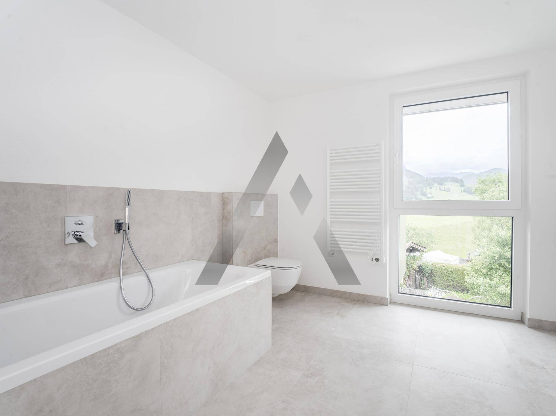 Modernes Badezimmer mit Badewanne, Wand-WC und großem Fenster mit Blick ins Grüne.