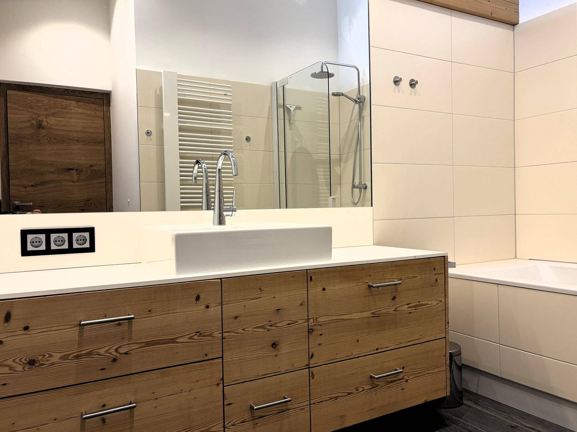 Modernes Badezimmer mit Holzwaschtisch, großem Spiegel und begehbarer Dusche.