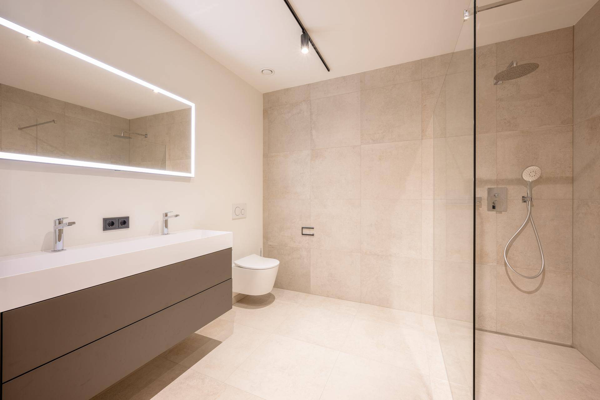 Geräumiges Badezimmer mit begehbarer Dusche, Doppelwaschbecken und wandhängendem WC.