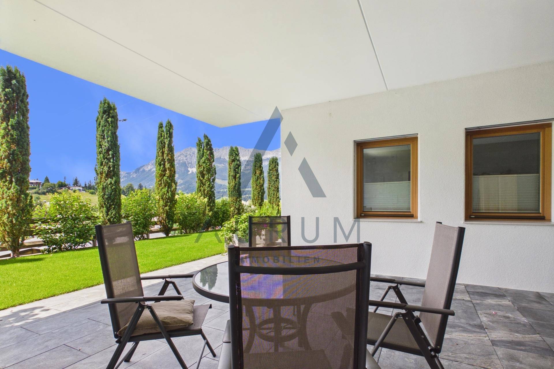 Gemütliche Terrasse mit Gartenmöbeln, umgeben von Grünflächen und beeindruckendem Bergblick.
