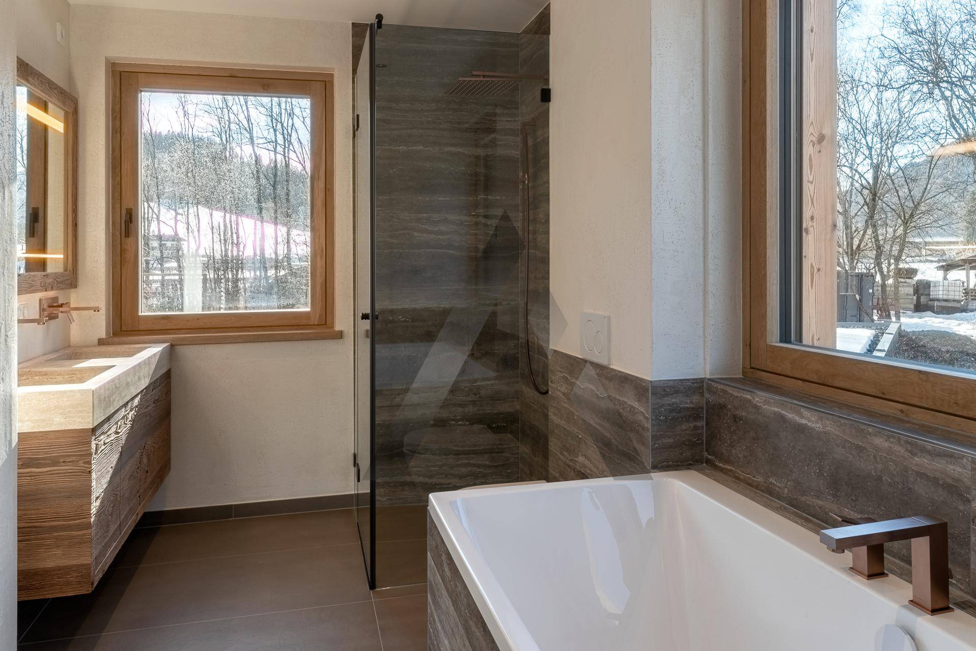Modernes Badezimmer mit Badewanne, begehbarer Dusche und Fenster mit Blick ins Grüne.