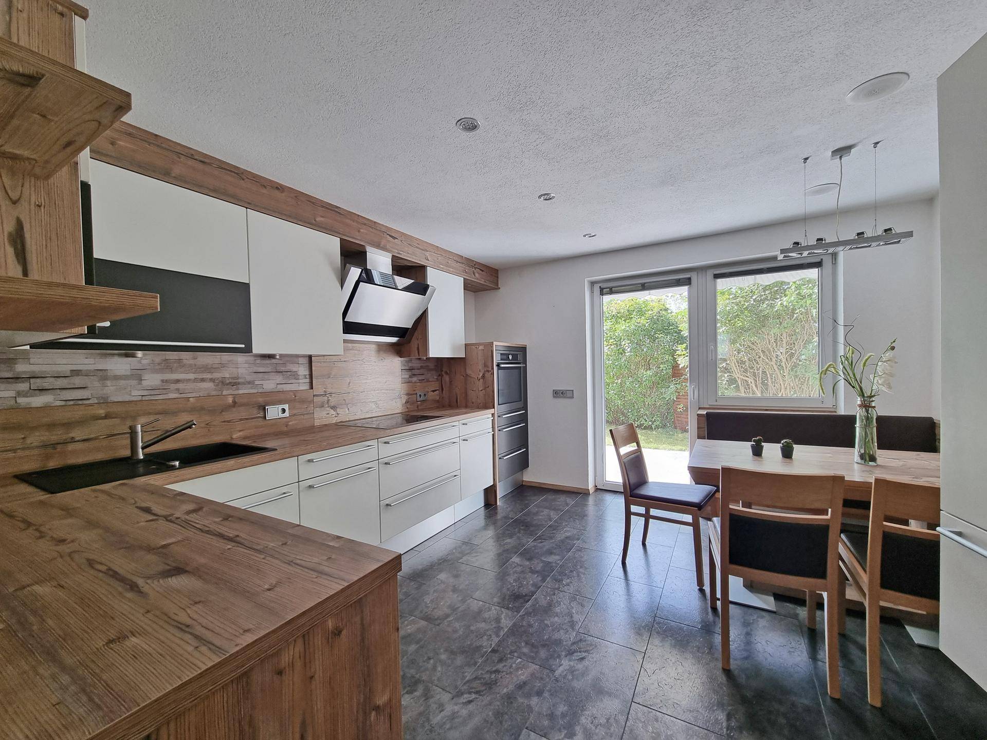 Moderne Küche mit Holzarbeitsplatten, Essbereich und direktem Zugang zum Garten.