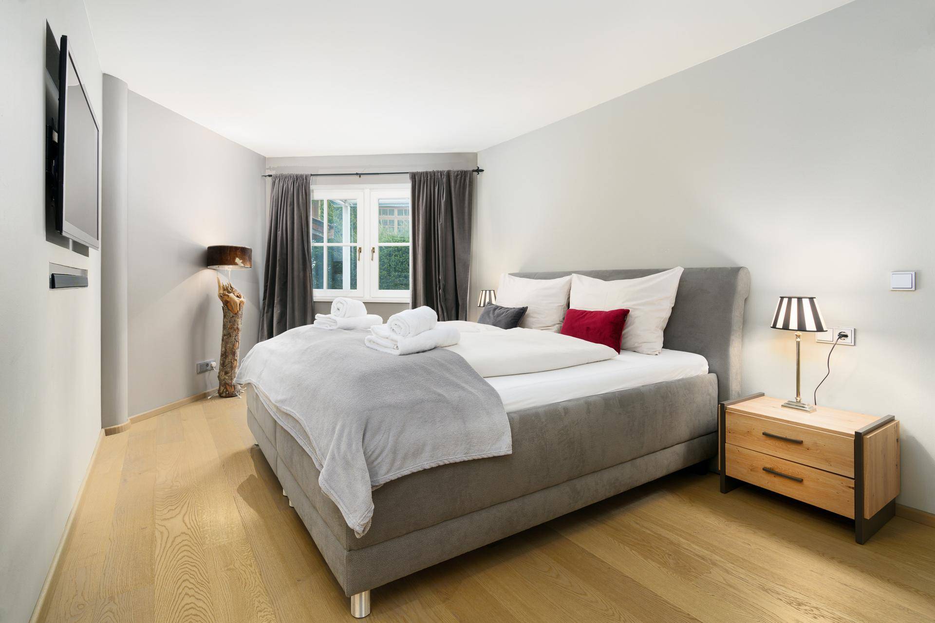 Gemütliches Schlafzimmer mit Doppelbett, Holzboden und Blick ins Grüne.