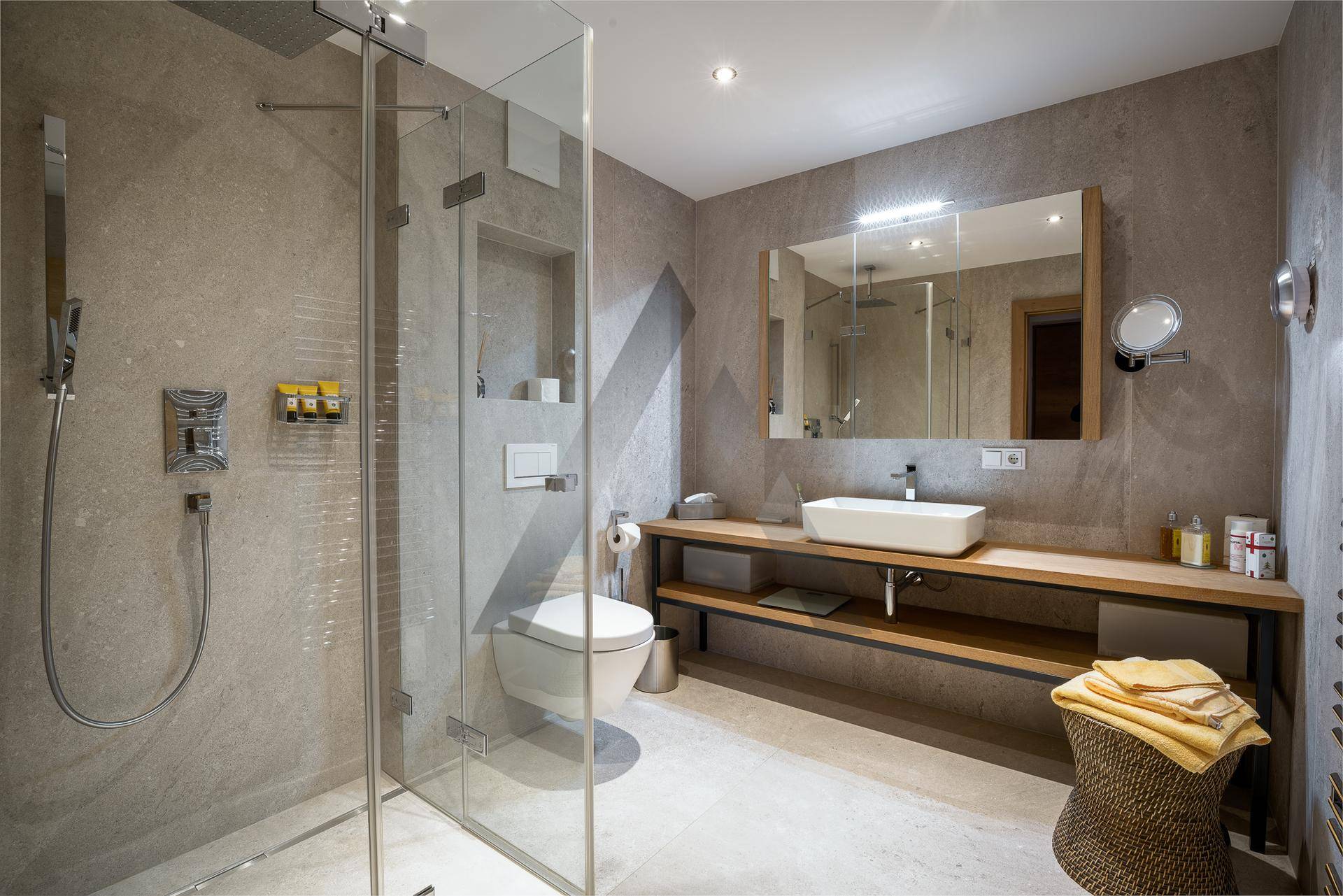 Modernes Badezimmer mit ebenerdiger Dusche, Wand-WC und stilvollem Waschtisch, in hellen Grautönen gehalten.