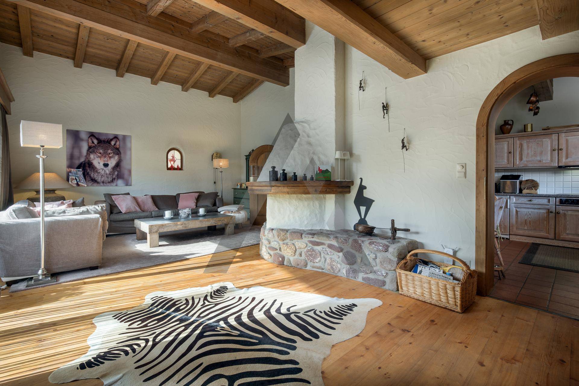 Gemütliches Wohnzimmer mit Holzboden, Kamin und sichtbaren Deckenbalken in alpiner Atmosphäre.