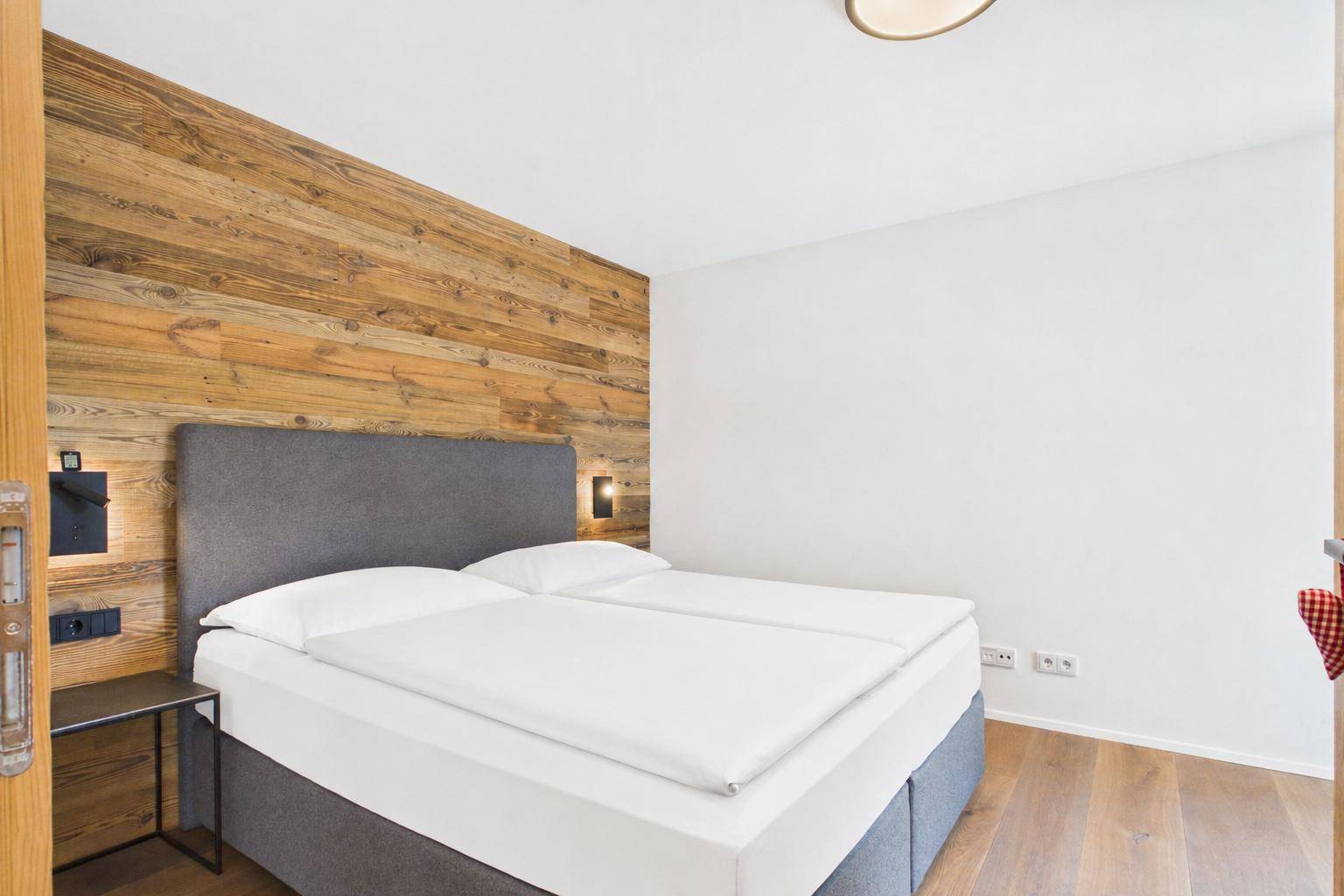 Gemütliches Schlafzimmer mit einer Akzentwand aus Holz und einem komfortablen Doppelbett.